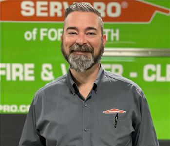 White male smiling in front of SERVPRO truck