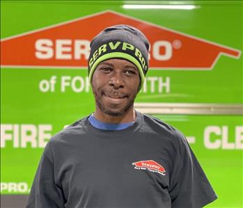 Black male smiling in front of SERVPRO truck