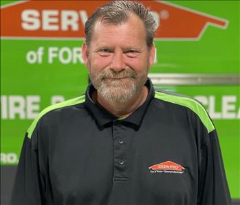 White male smiling in front of SERVPRO truck