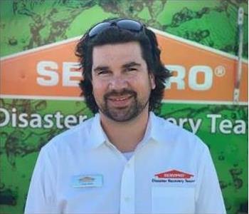 White male smiling in front of SERVPRO sign