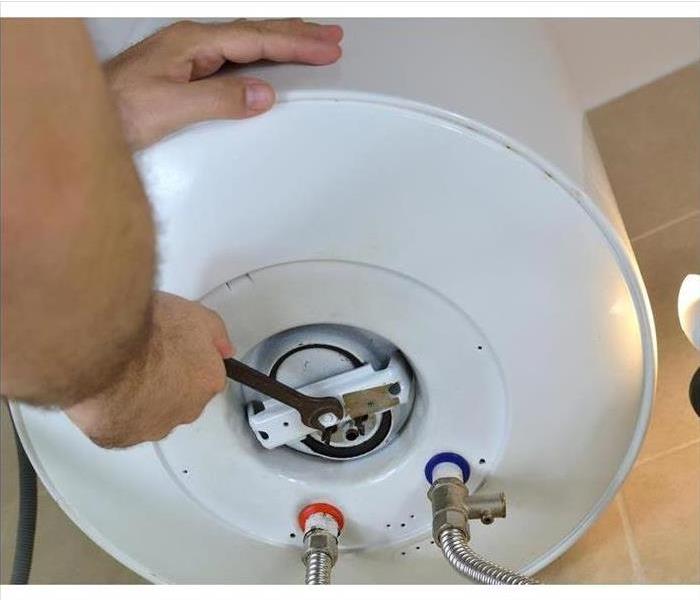 a person using a tool on a white water heater