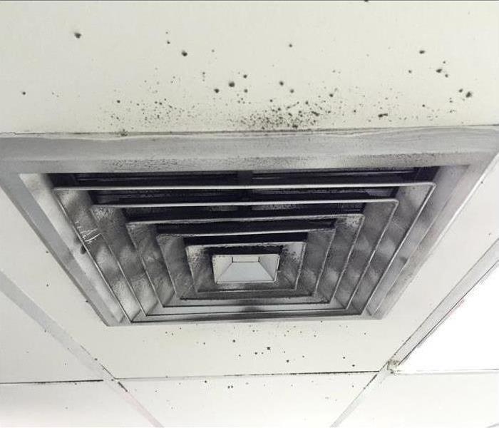 Air vent in ceiling with black spots around it.